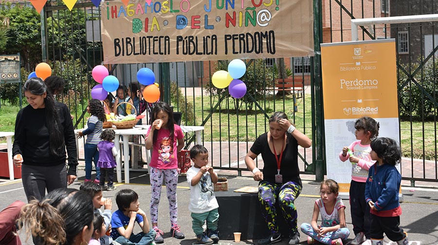 niños disfrutan en un parque junto a la promotora de lectura de la celebración del día de los niños