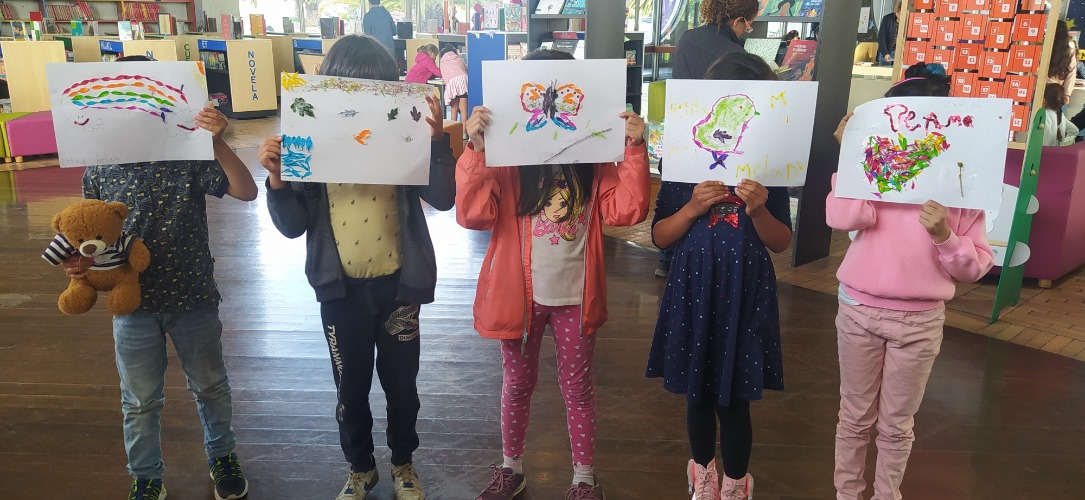 Niños y niñas en la biblioteca con dibujos