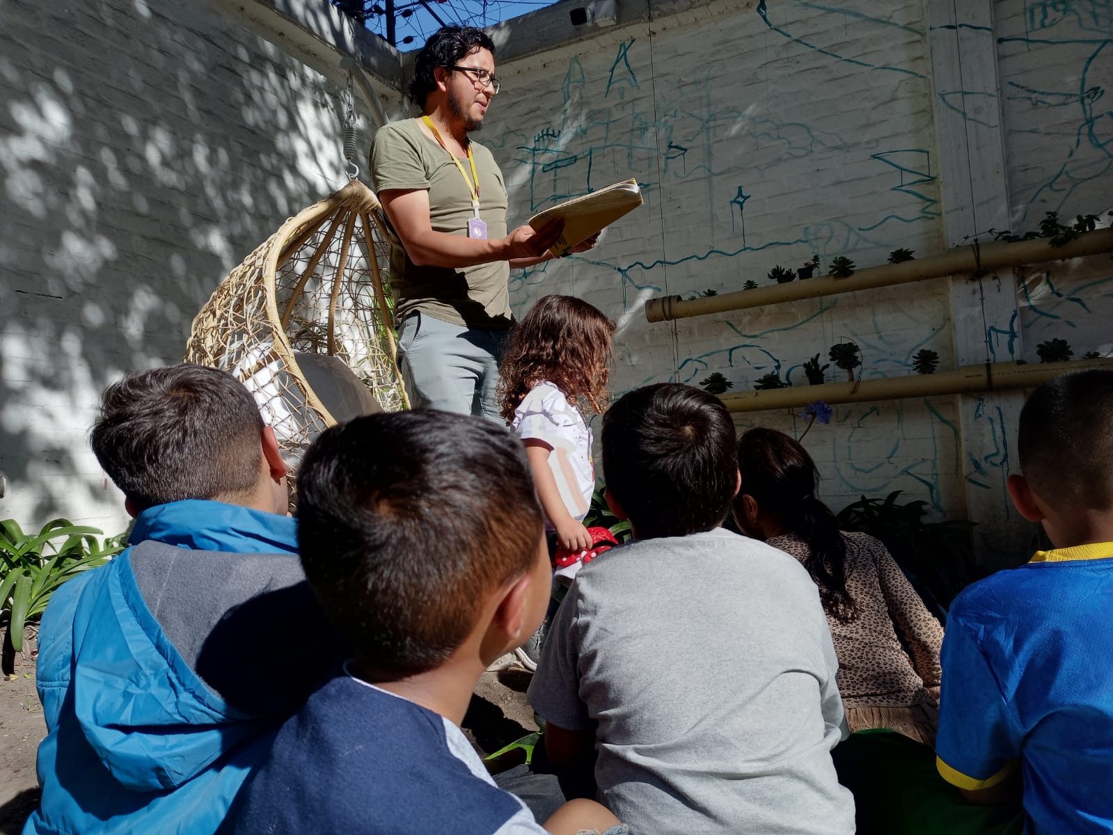 Niñas y niños ponen atención a lectura al aire libre