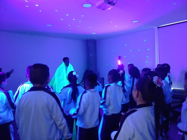 niños y niñas jugando en medio de un cuarto con luz azul