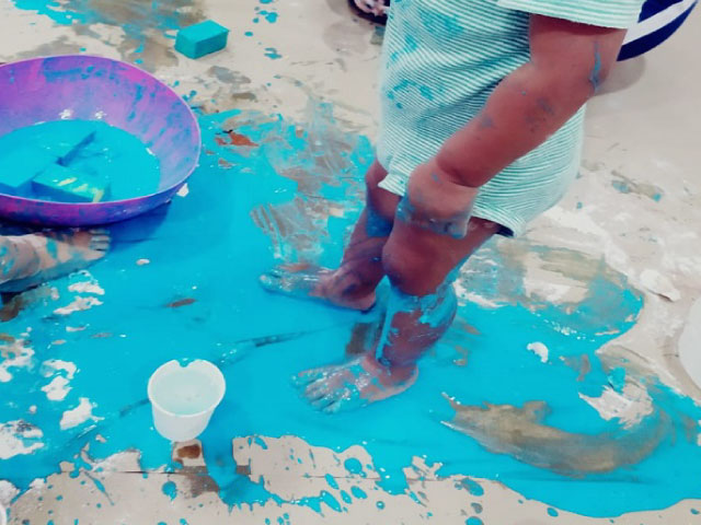 niño pequeño caminando descalzo sobre pintura azul
