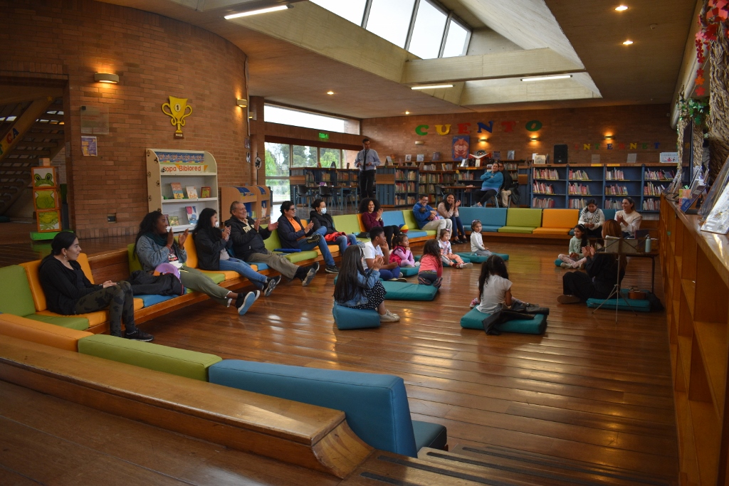 Niños y niñas con acompañantes participando de la Hora del Cuento en la biblioteca