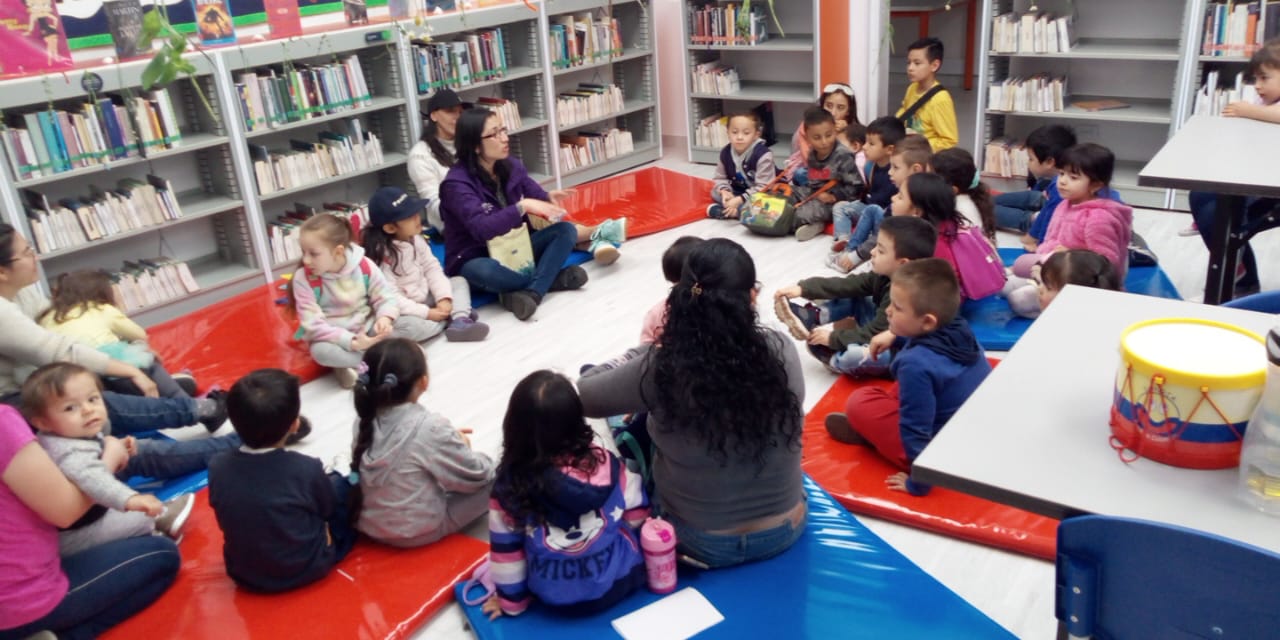Niñas, niños y acompañantes participando de actividad en biblioteca