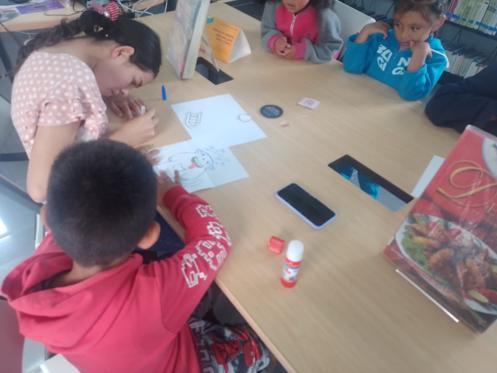 Niño y niñas dibujando en la biblioteca