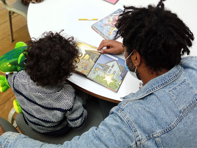 Bebé junto a acompañante disfrutando las imágenes de un libro ilustrado