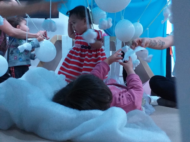 bebés jugando con globos blancos junto a sus cuidadores y padres.