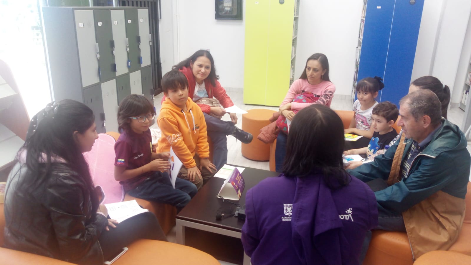 niñas, niños y padres conversando en compañía de una docente que guía la actividad.