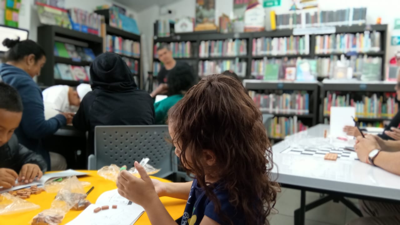 una niña pequeña en medio de un taller de plastilina en una biblioteca.