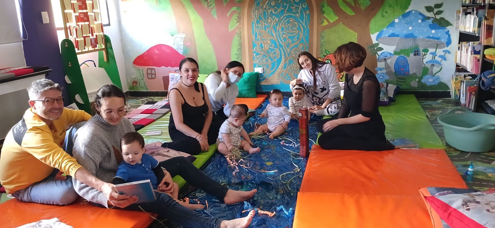 padres acompañando a sus hijos a un taller con la docente donde están leyendo en voz alta.