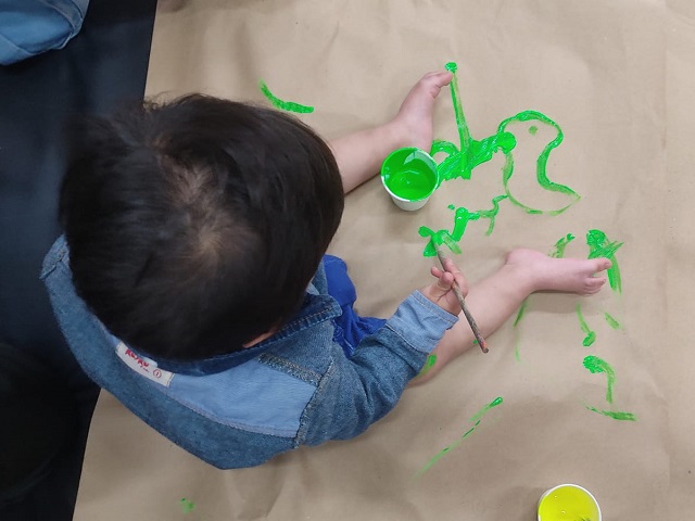 Bebé utilizando pintura verde sobre papel