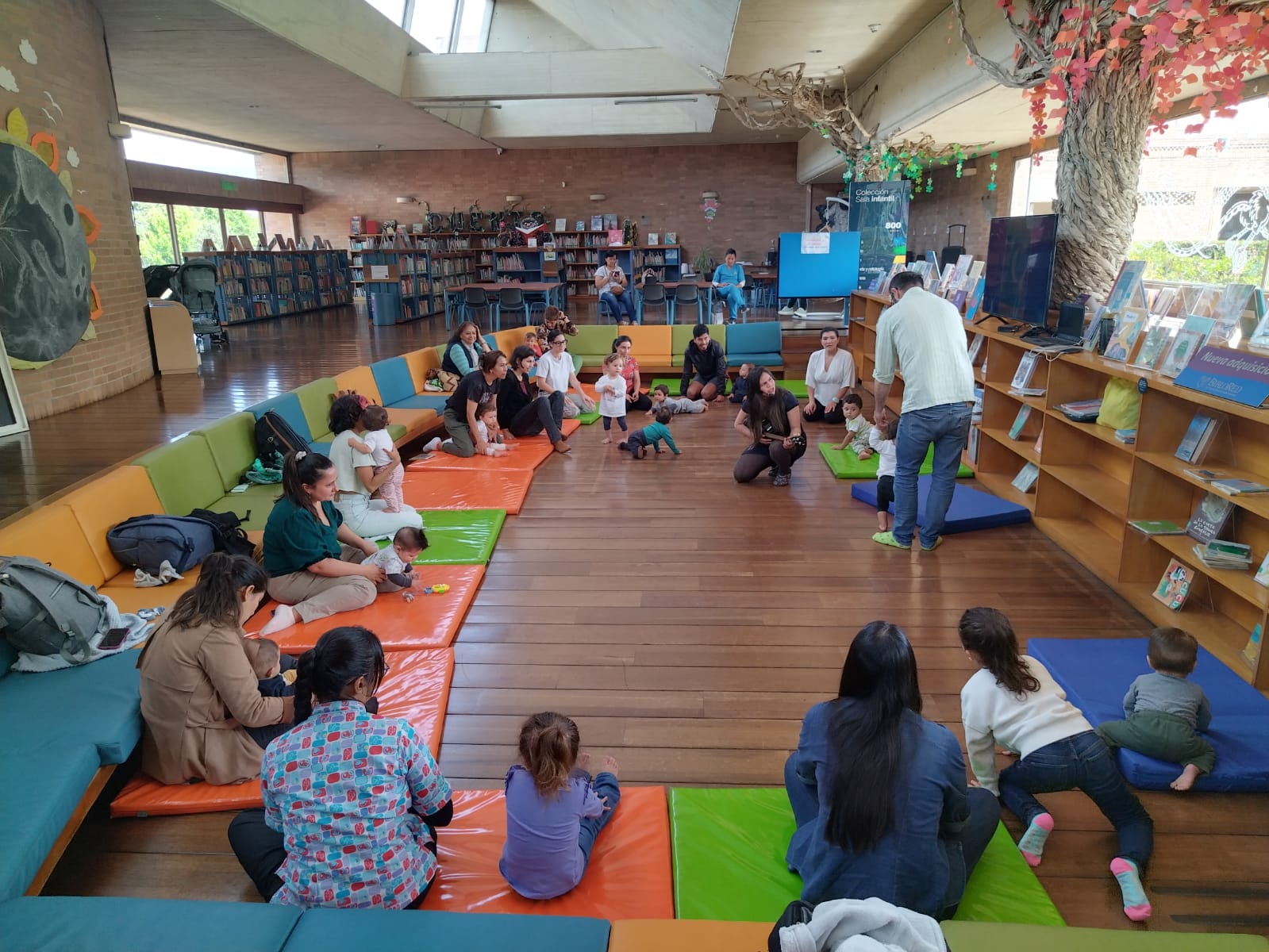 Bebés y acompañantes participando de actividad en la sala infantil de la biblioteca