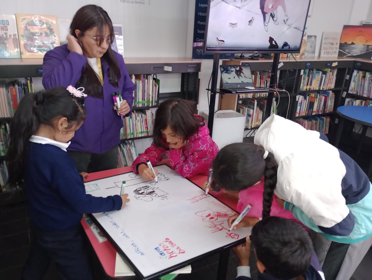 grupo de niños dibujando sobre un tablero junto a su docente