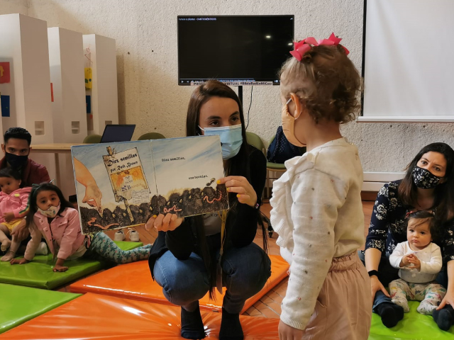 una niña pequeña viendo un libro que le enseña una profesora