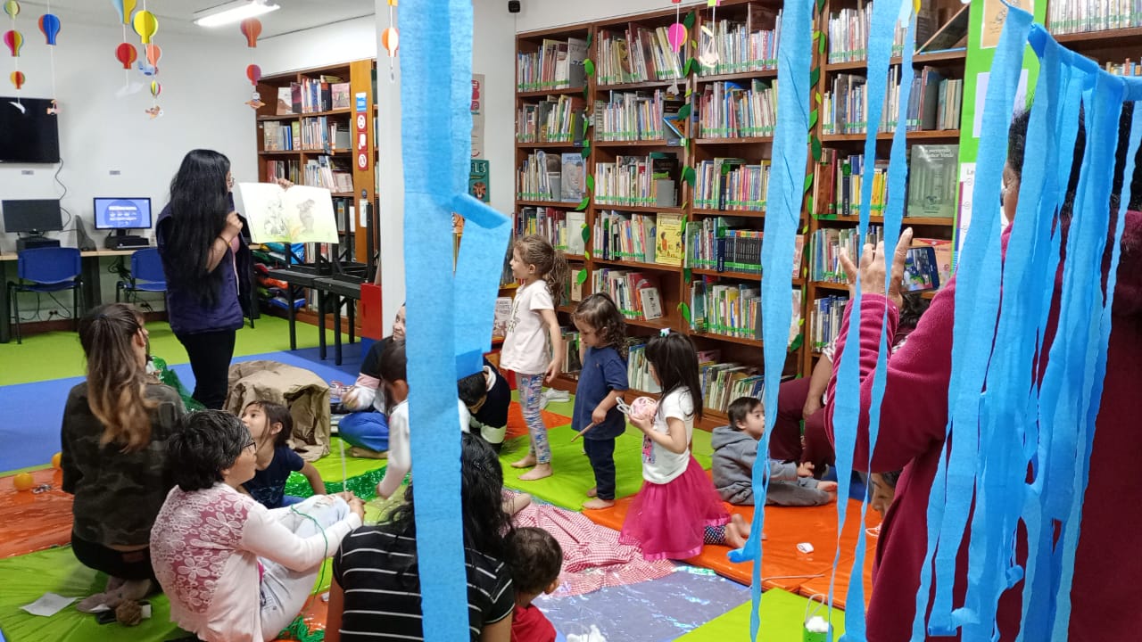 niñas y niños jugando junto a sus padres con largas tiras de color azul