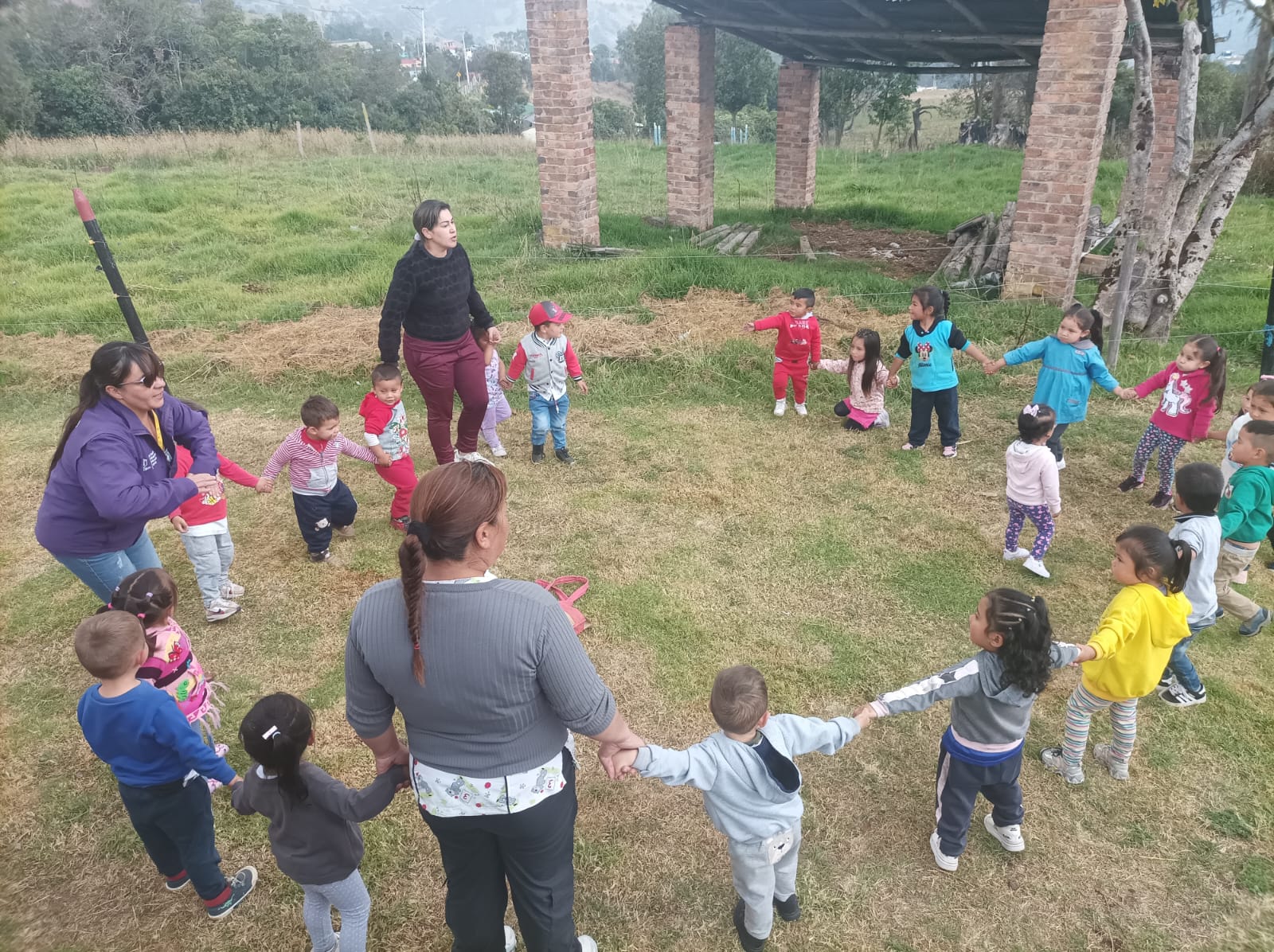 niños tomados de la mano en círculo jugando al aire libre
